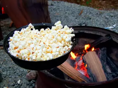 popcorn in a pan next to fire
