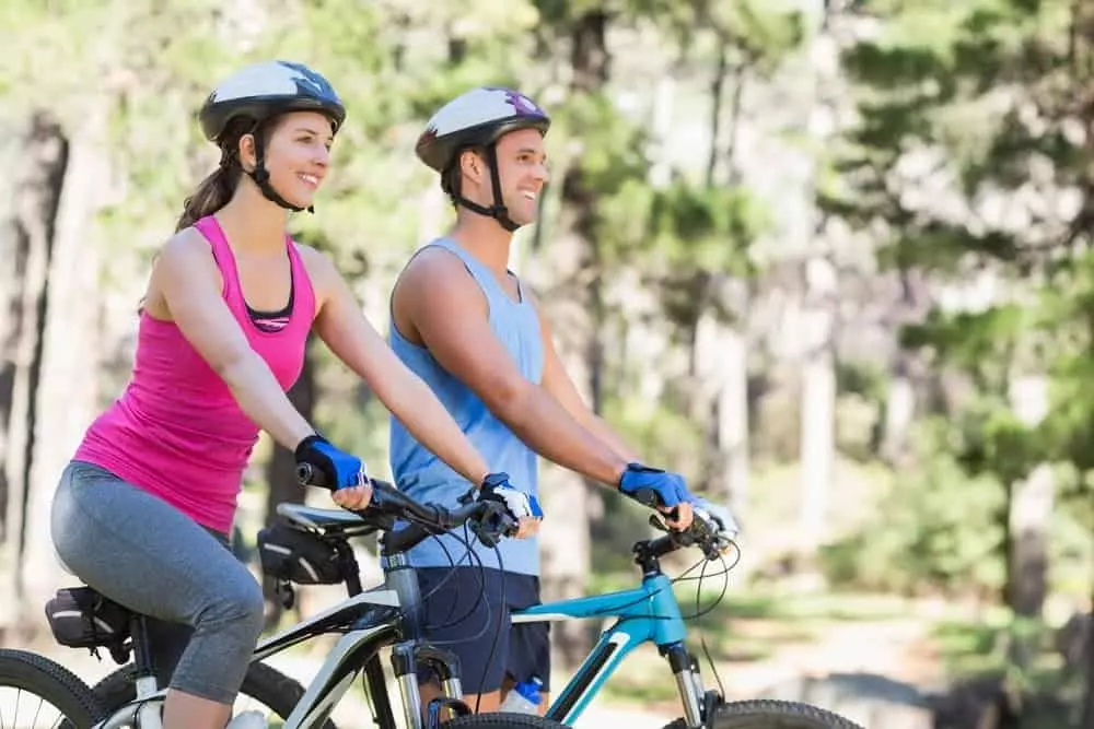 happy couple riding bicycles in forest