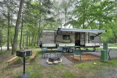 chairs around fire pit with grill and picnic table near an rv