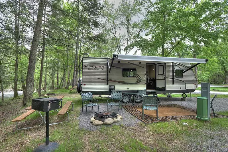 chairs around fire pit with grill and picnic table near an rv