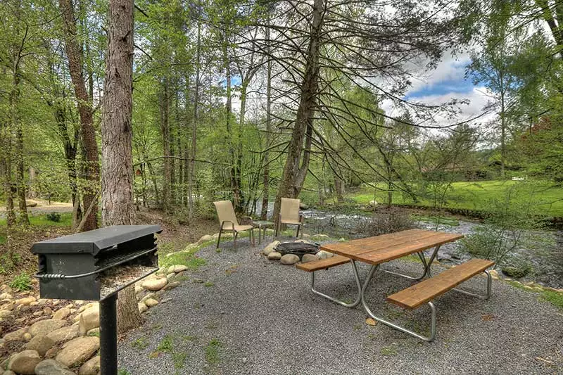 picnic area with a grill next to a creek