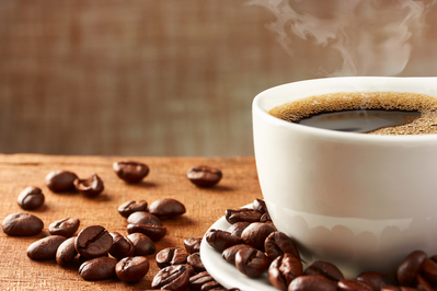 hot cup of coffee surrounded by coffee beans